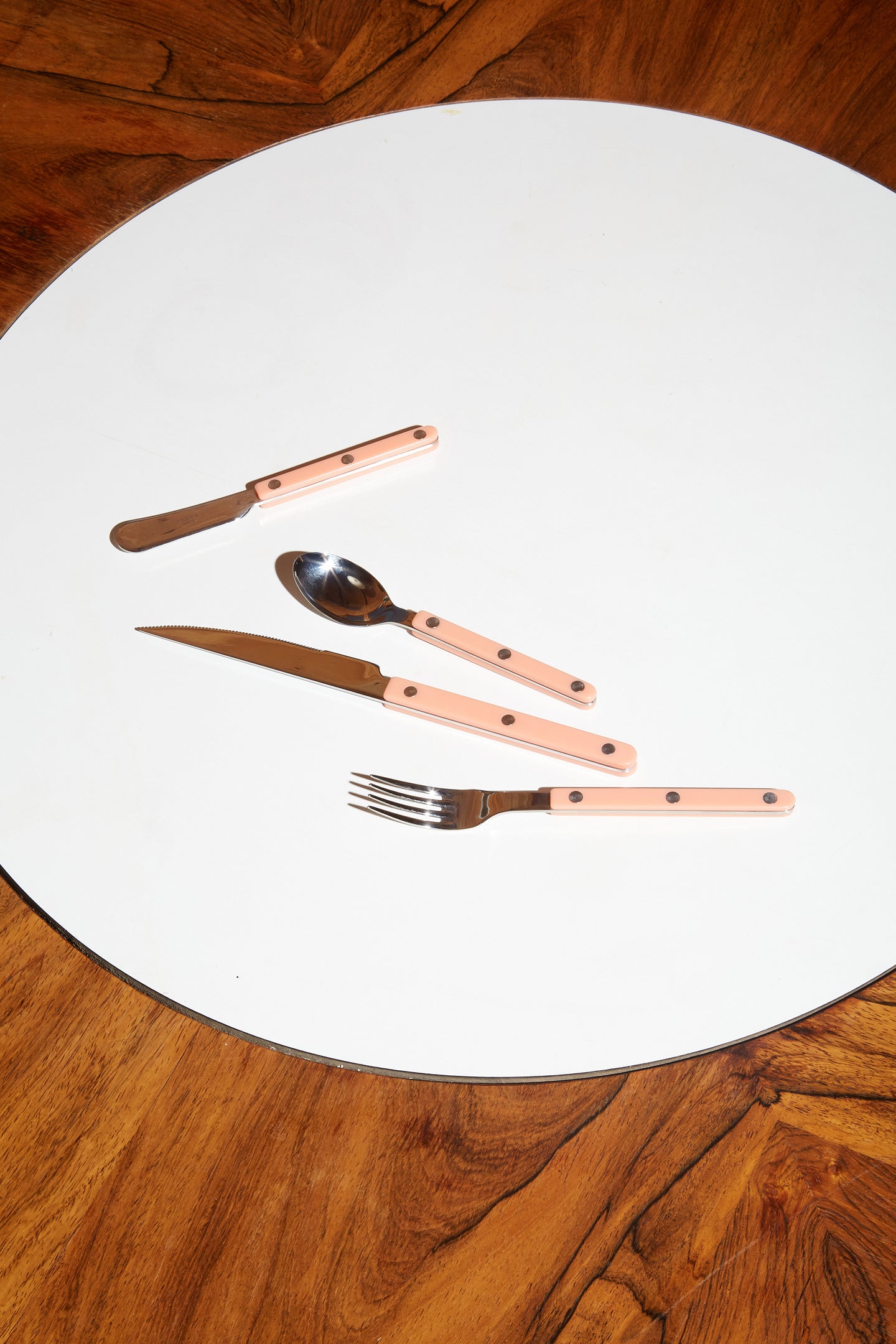 Four pieces of Sabre bistro flatware in pastel coral.