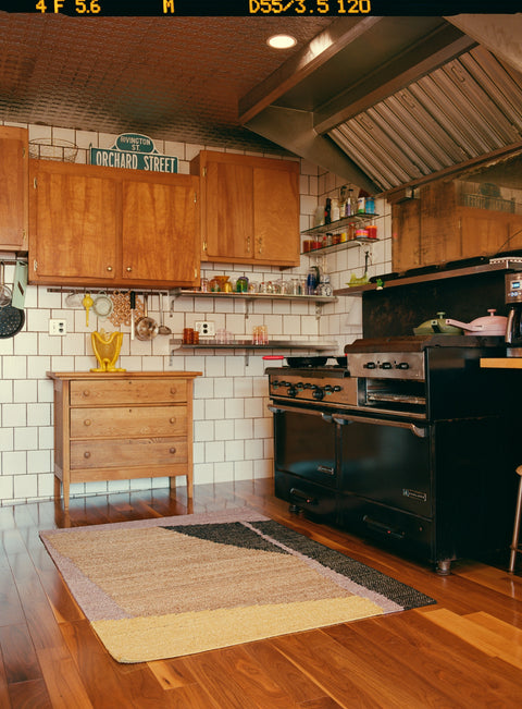 The Ocean Moon Rug by Cold Picnic in a mostly wooden kitchen.