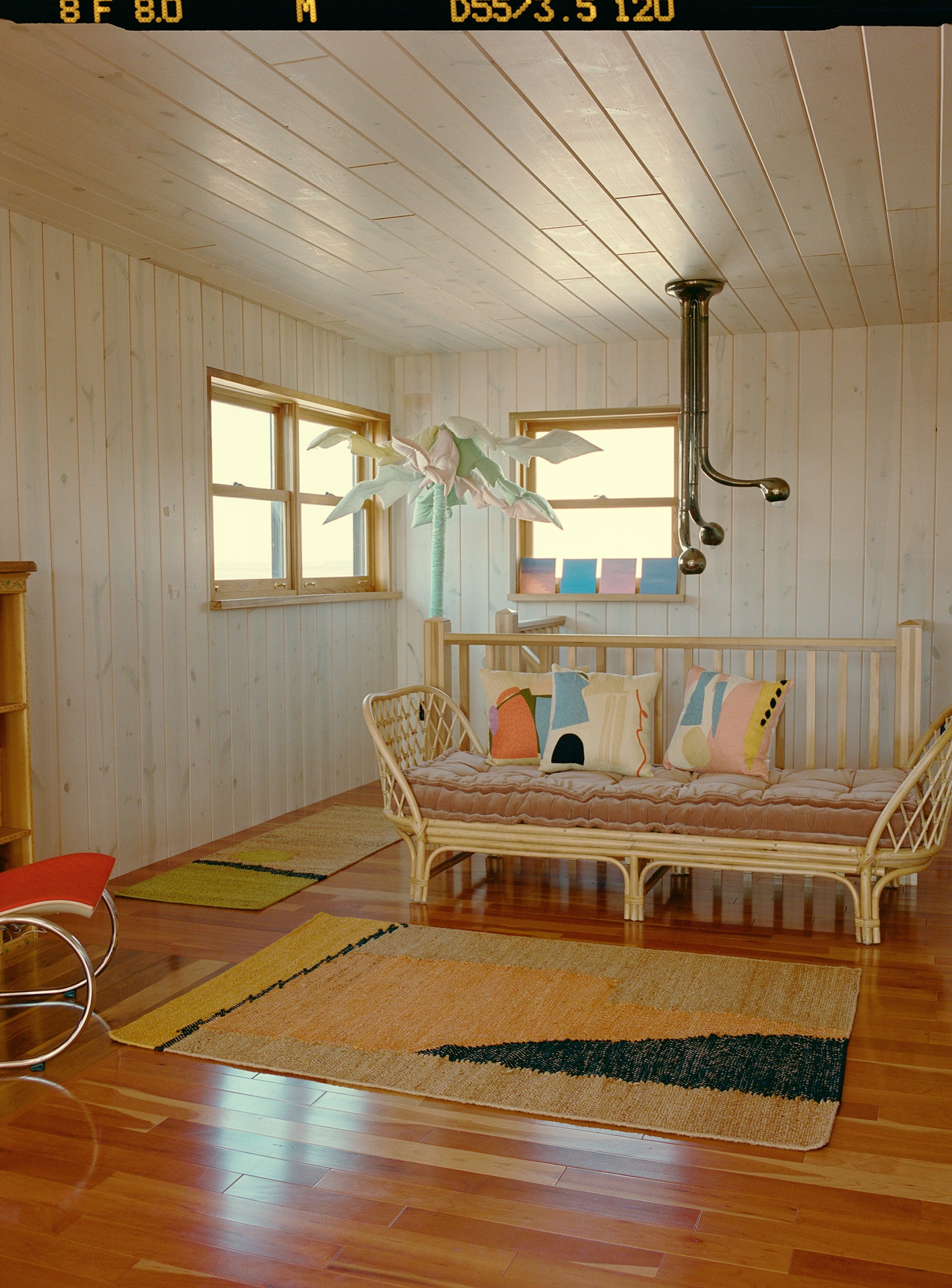 Outside Over There Rug in a living space with rattan furniture and wooden floors and walls.