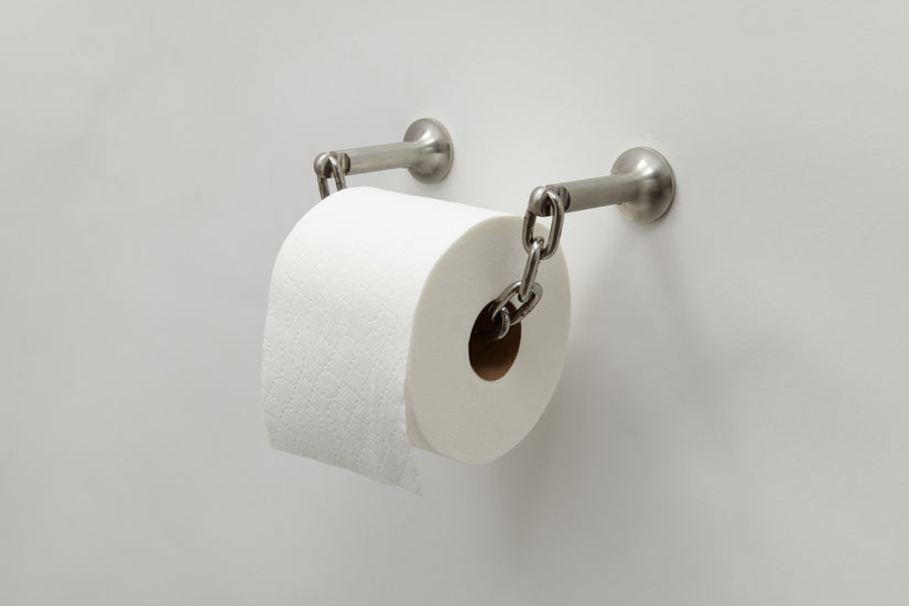 Catena Toilet Paper Holder by Chen and Kai mounted to a white wall with a roll of toilet paper.