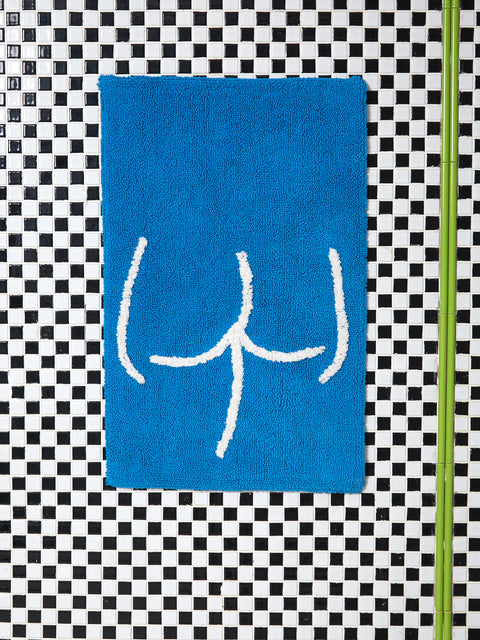 A blue tushy bathmat against black and white checkered tile.