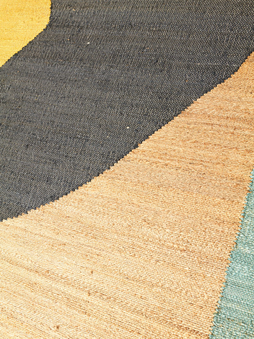 Close up of the natural hemp, black, yellow, and teal abstract pattern.