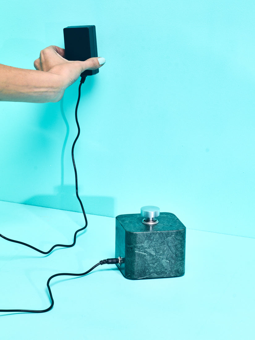 A hand demonstrating the wall plug power supply of the Houseplant Car Lighter.