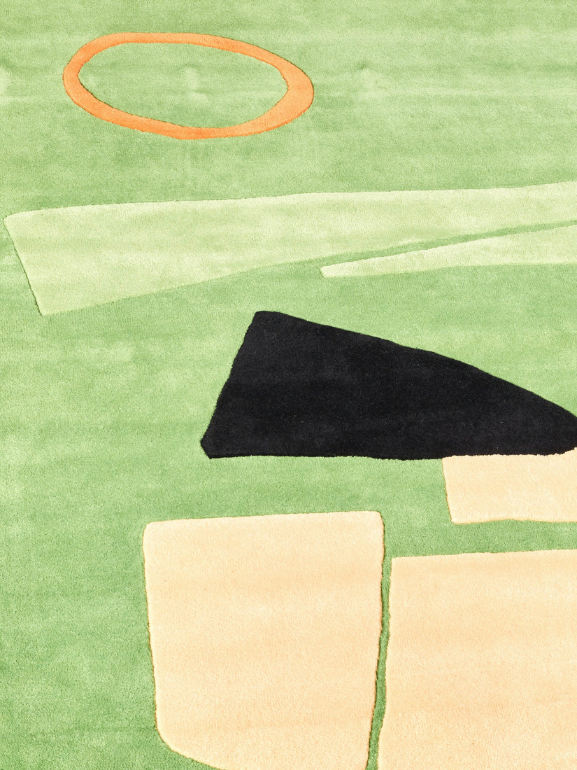 Close up of the mostly green rug with abstract accents of orange, lighter green, cream, and black.