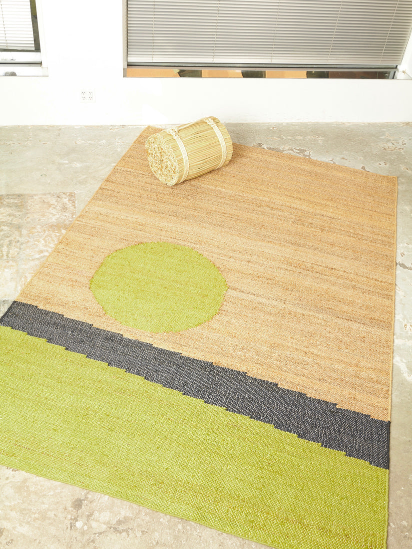 The Changeling Rug by Cold Picnic in 6x9 on a concrete floor styled with a rattan stool.
