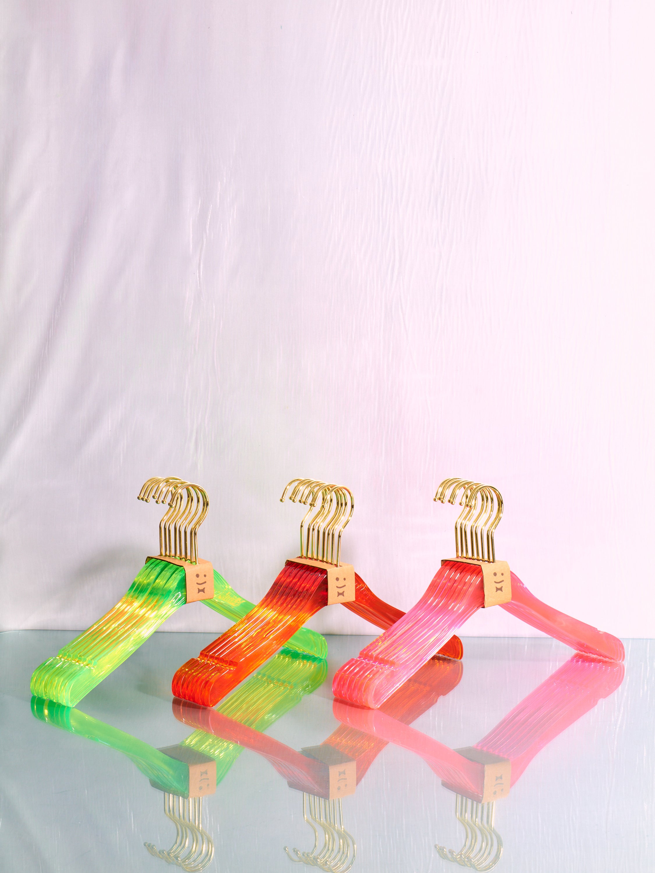 Pink, orange, and green sets of hangers by Staff.