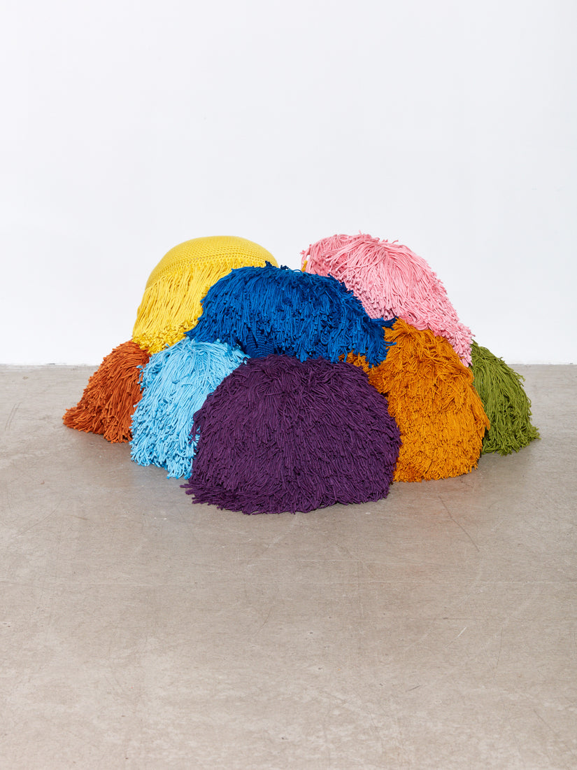 A mountain of Crochet Pillows by Huldra of Norway on a concrete floor.