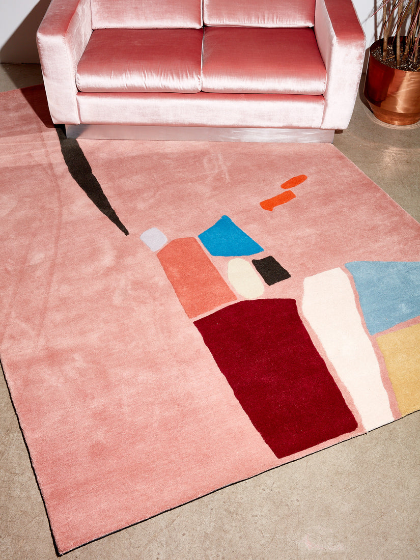 Mostly pink rug with abstract accents of blues, orange, pink, white, black, maroon, and more.