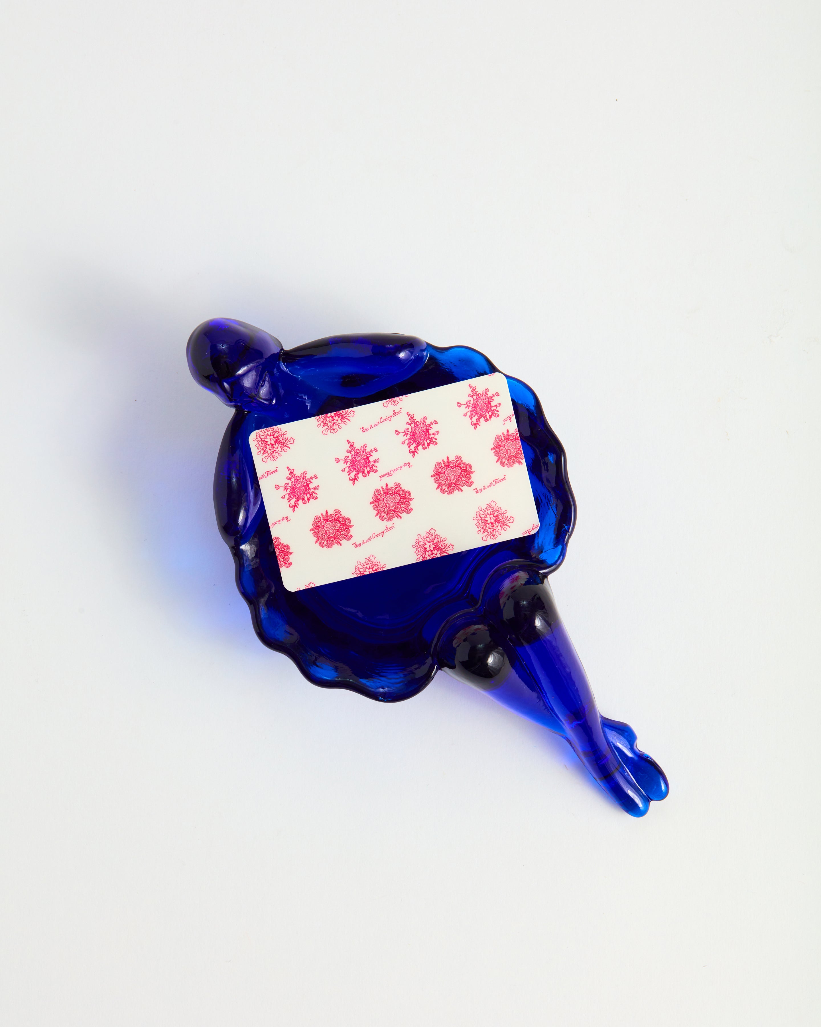 A pink floral printed gift card sits inside a cobalt blue bathing lady dish.