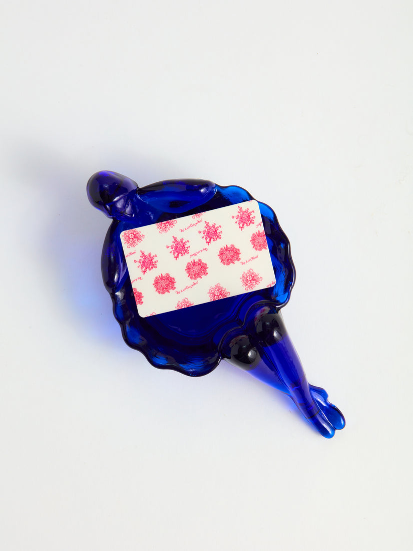 A pink floral printed gift card sits inside a cobalt blue bathing lady dish.