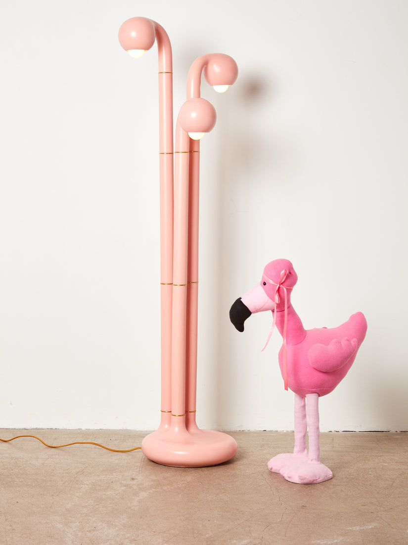 A stuffed flamingo sits next to the 3-globe ceramic floor lamp by Entler.