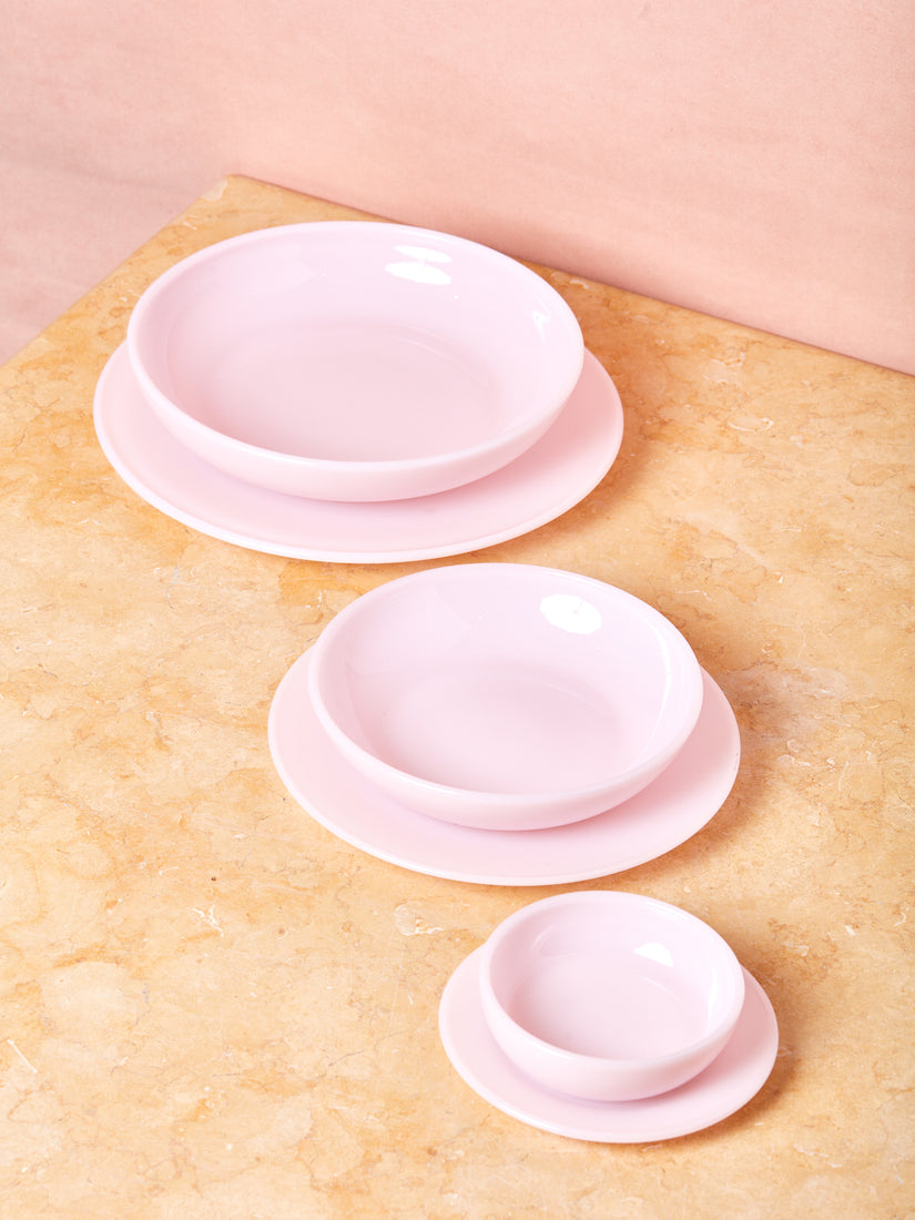 Pink Milk Glass Dinnerware by Mosser bowls and plates stacked by size. The Bowls sit atop their corresponding plate.