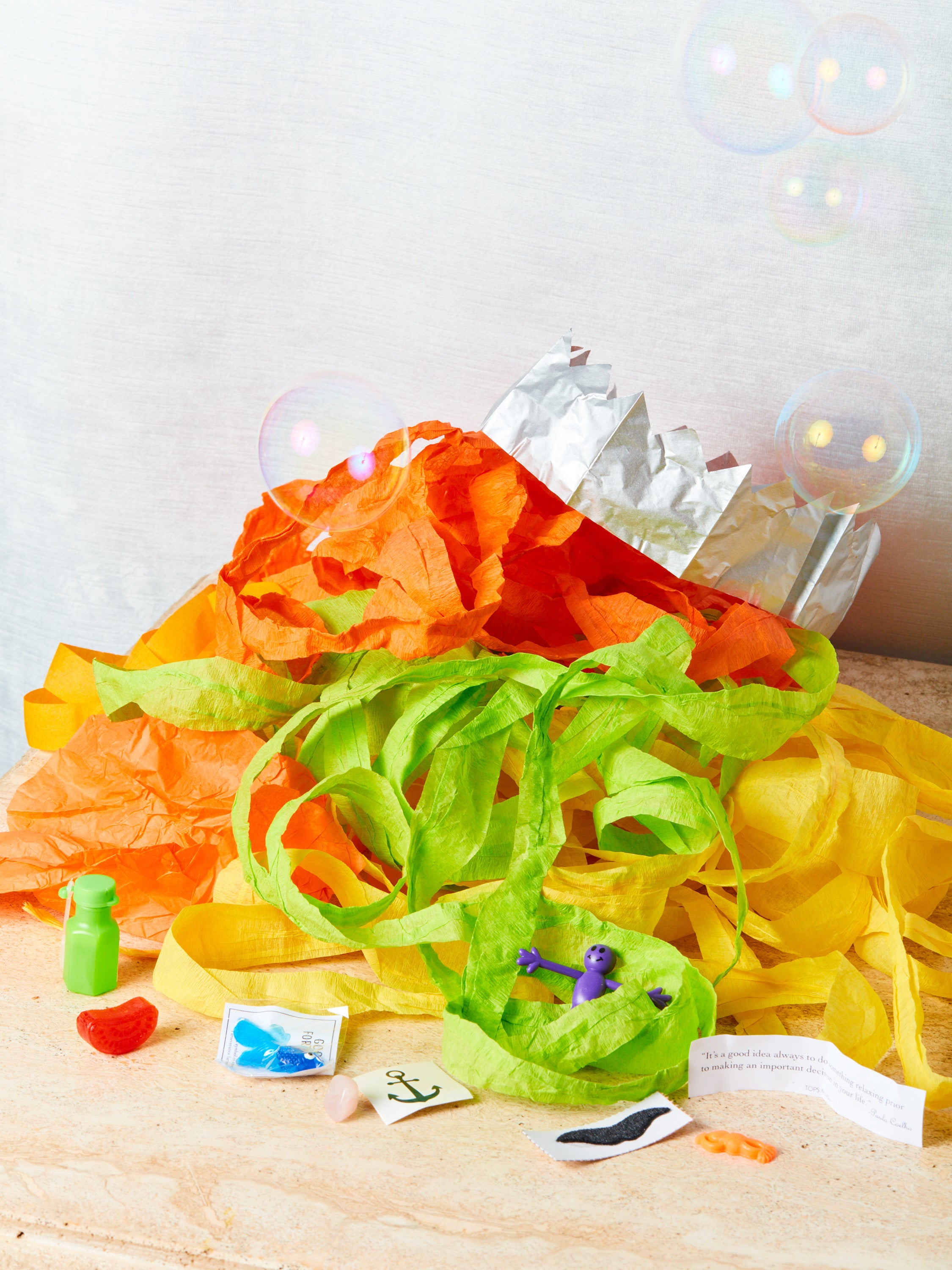 An unraveled pile of streamers with prizes displayed all around and bubbles fill the air.