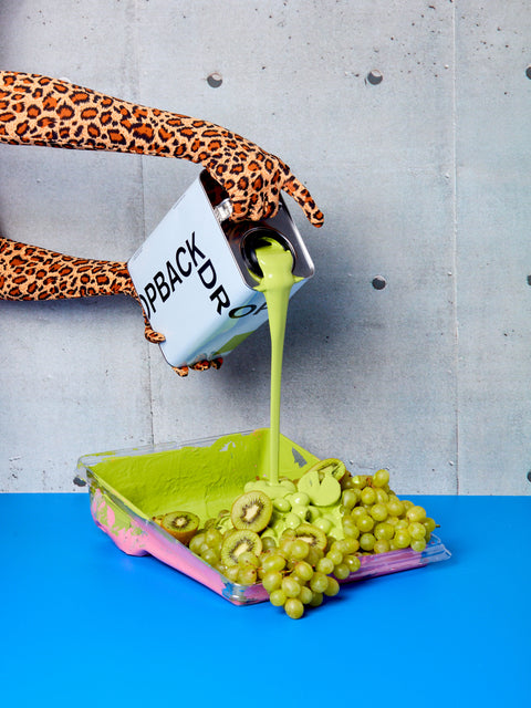 "Pretty Ugly" green paint being poured into a roller tray full of green fruit.