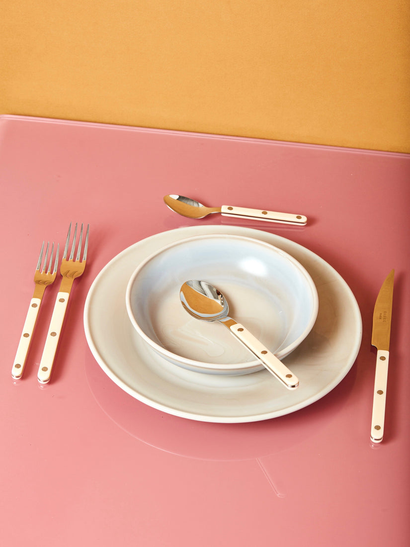 A set of Sabre bistro flatware in ivory with a place setting of Mosser dinnerware.