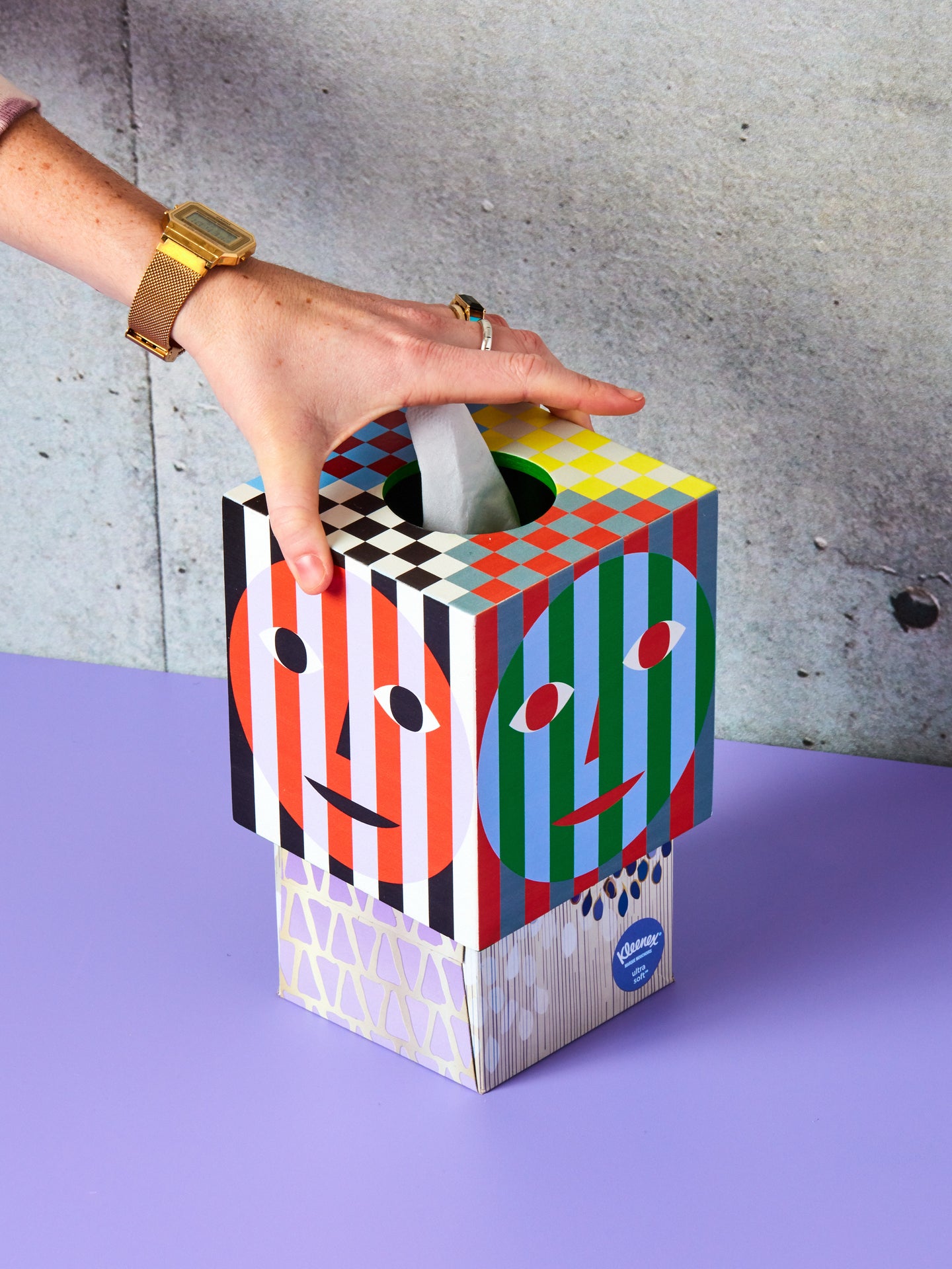 A hand lifts the Dusen Dusen Tissue Box Holder up revealing the kleenex box underneath.