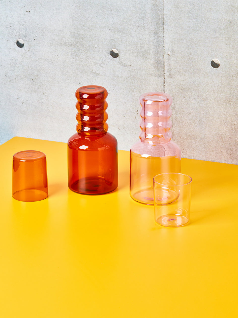Pink and Amber bedside carafes with Ripple Cups by Sophie Lou Jacobsen in place of their original cups.