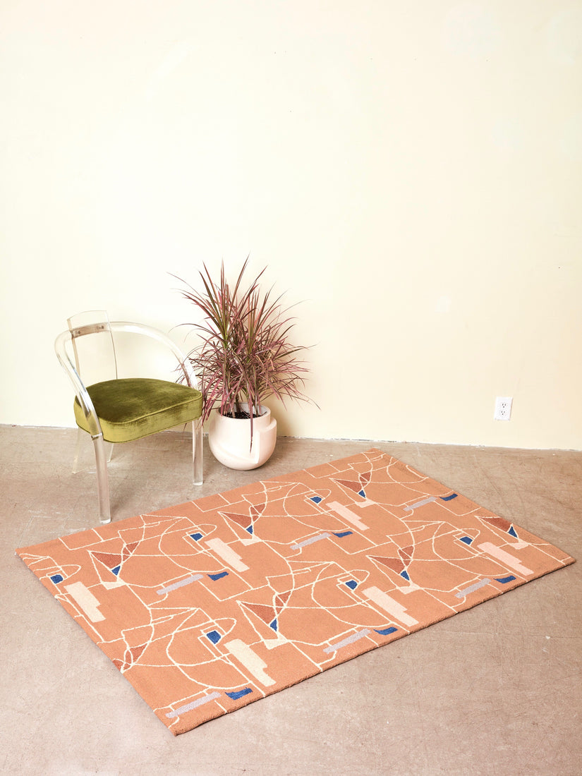 The Long Goodbye Rug by Cold Picnic with a lucite loop chair and a plant in a white pot.