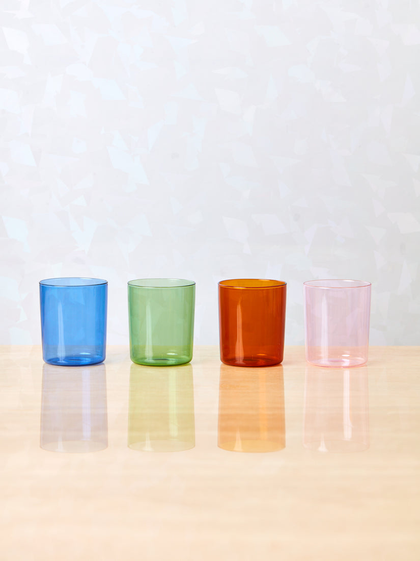 Blue, green, amber and pink cups by Maison Balzac sitting in a straight line.