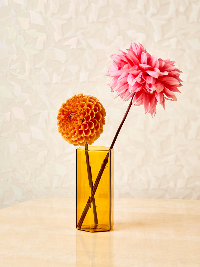A single honey Coucou glass with two flowers inside.