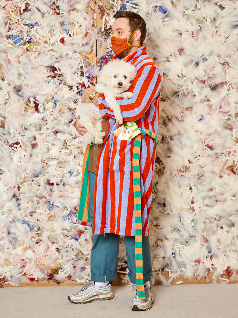 Max wears warm stripe robe by Dusen Dusen carrying a white fluffy dog.