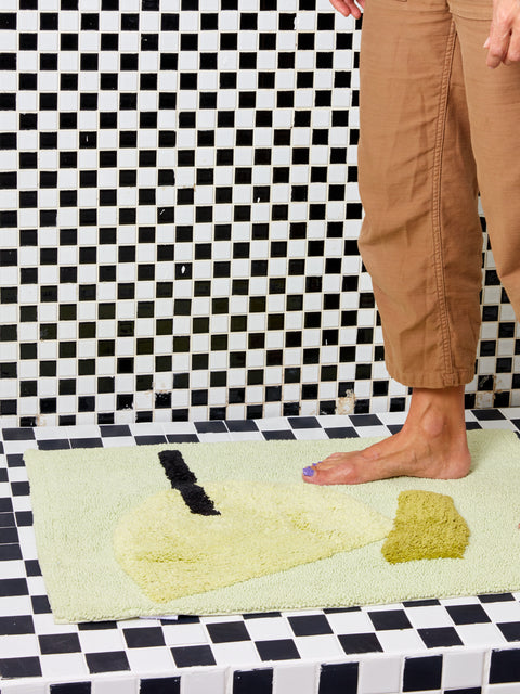 Someone stands barefoot on a medium Cool Bath Mat.