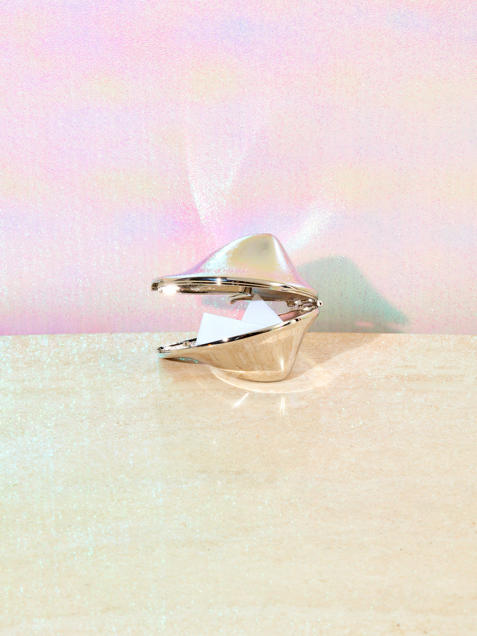 Chrome fortune cookie ajar showing its paper inside.