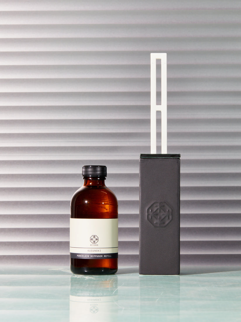 The Porcelain Diffuser by Kitowa sits right of a refill bottle of Kusunoki scent oil.