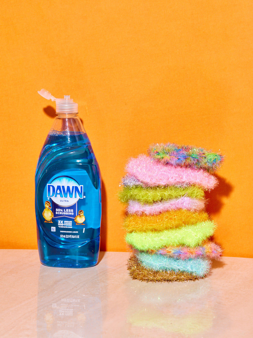 A stack of different colored sponges next to a bottle of Dawn dish soap.