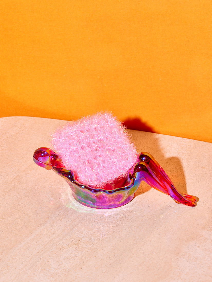 A single pink sponge inside of an iridescent red bathing lady dish by Mosser.