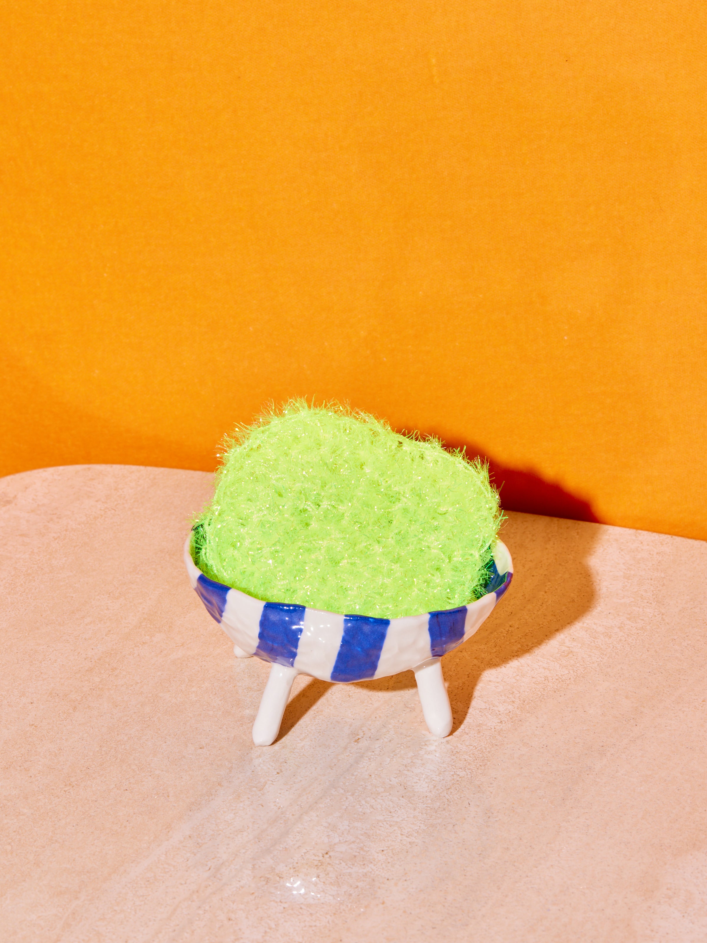 A single neon yellow sponge inside of an Isabel Halley soap holder.