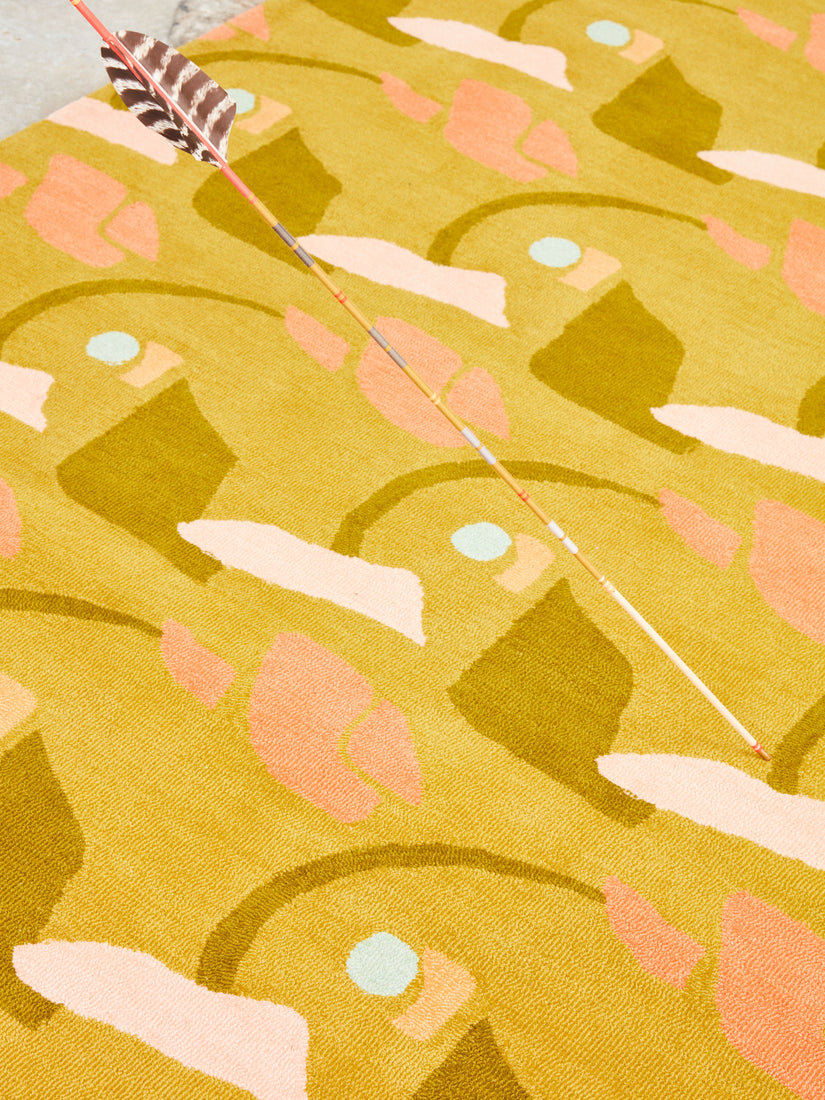 Close up of the The Aviary, Late Summer Rug by Cold Picnic with a long arrow stuck in it.
