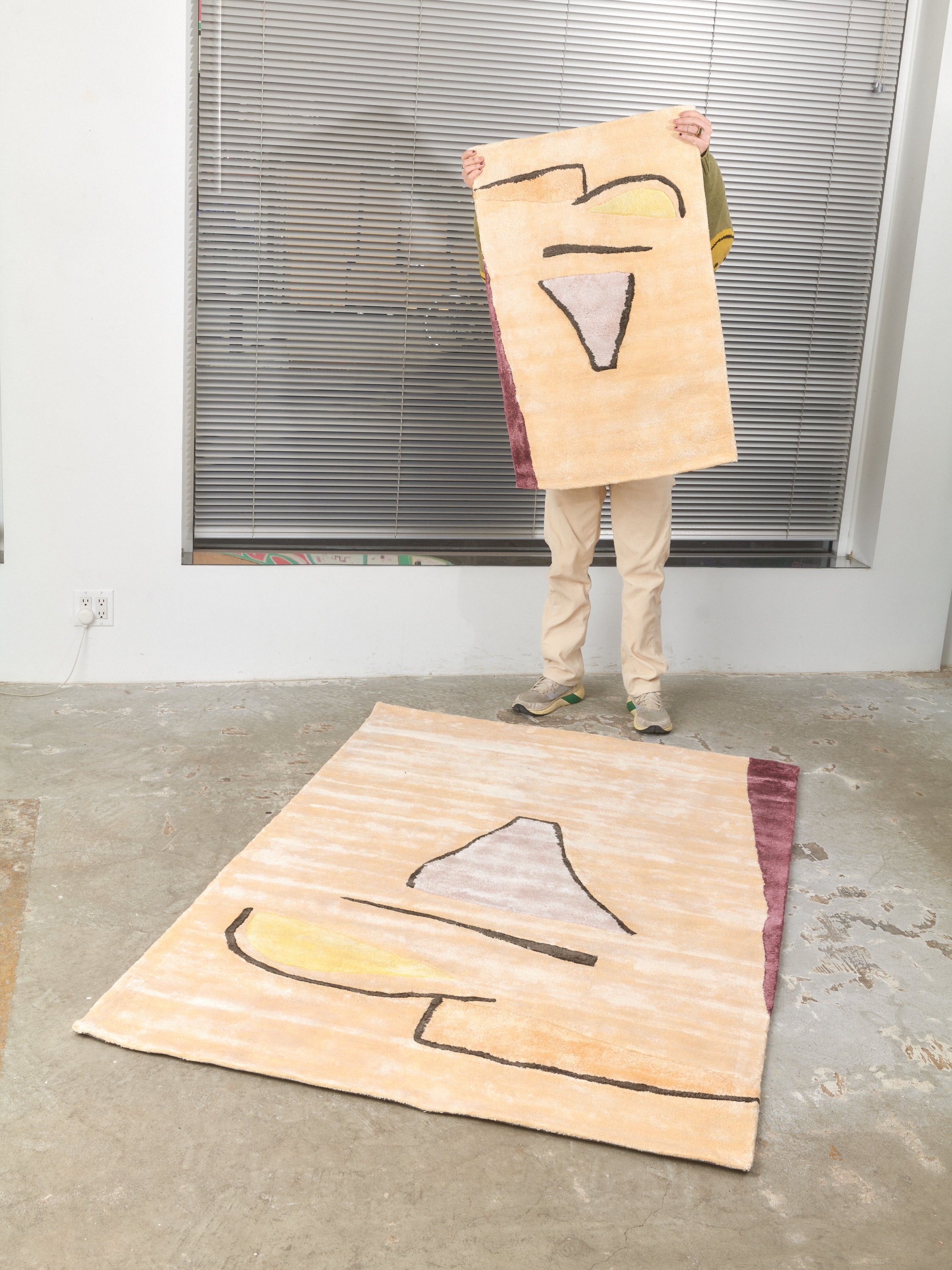 Someone holds up a 2x3 Sherbet Rug behind a 4x6 Sherbet Rug by Cold Picnic that lays on the floor.