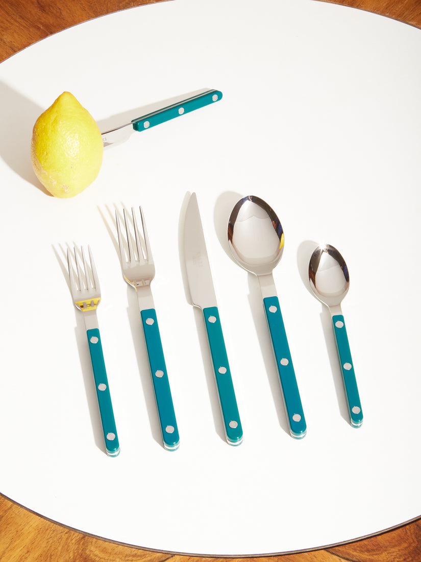 A place setting of Sabre Bistro Flatware in Teal. The spreader sits in an uncut lemon.