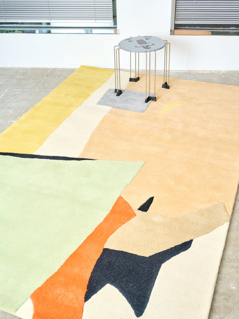 A grey triple play face table sits atop a Beauty is a Dangerous Thing Rug.