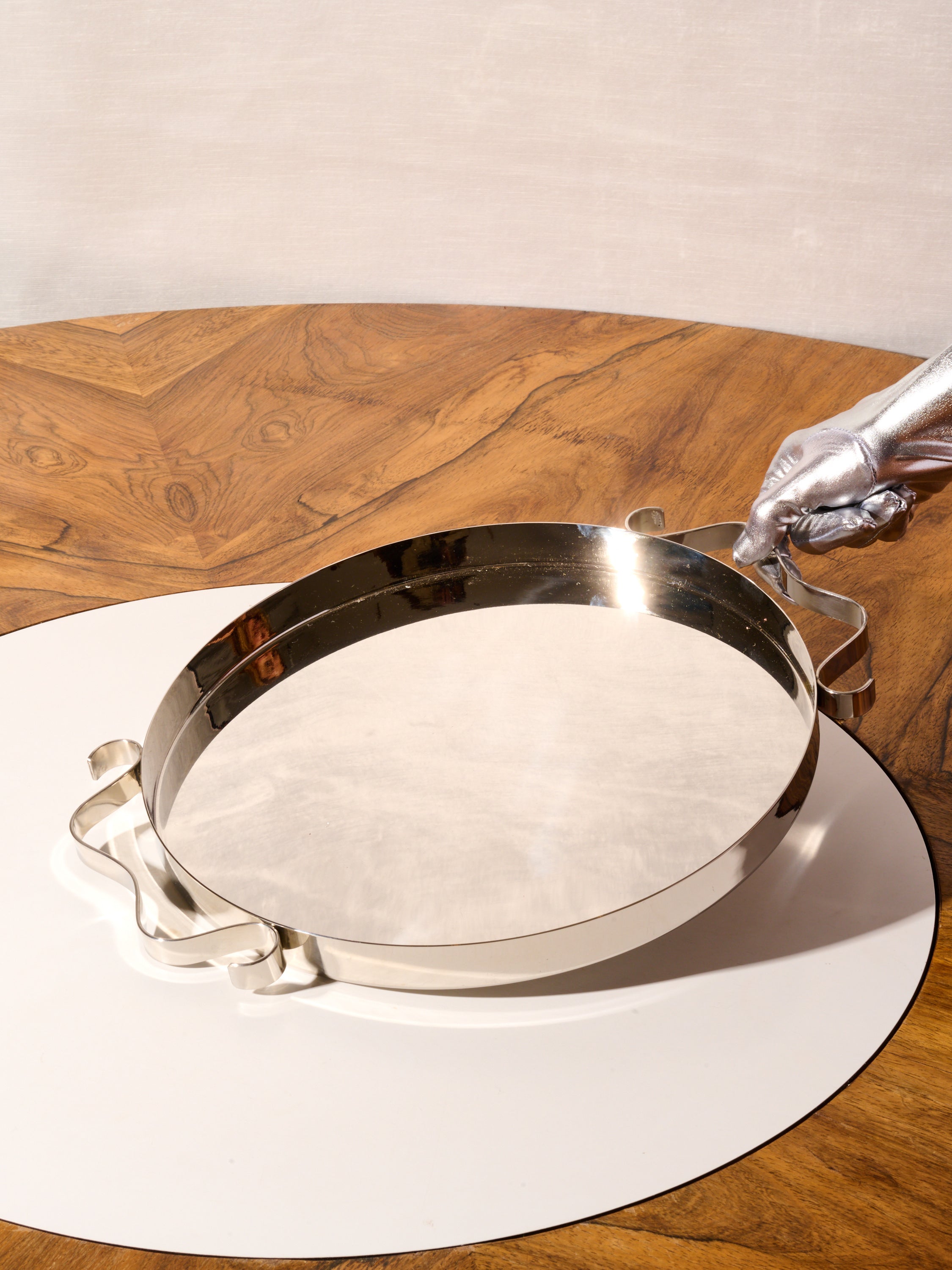 A silver gloved hand grabs one of the squiggle handles of the tray.