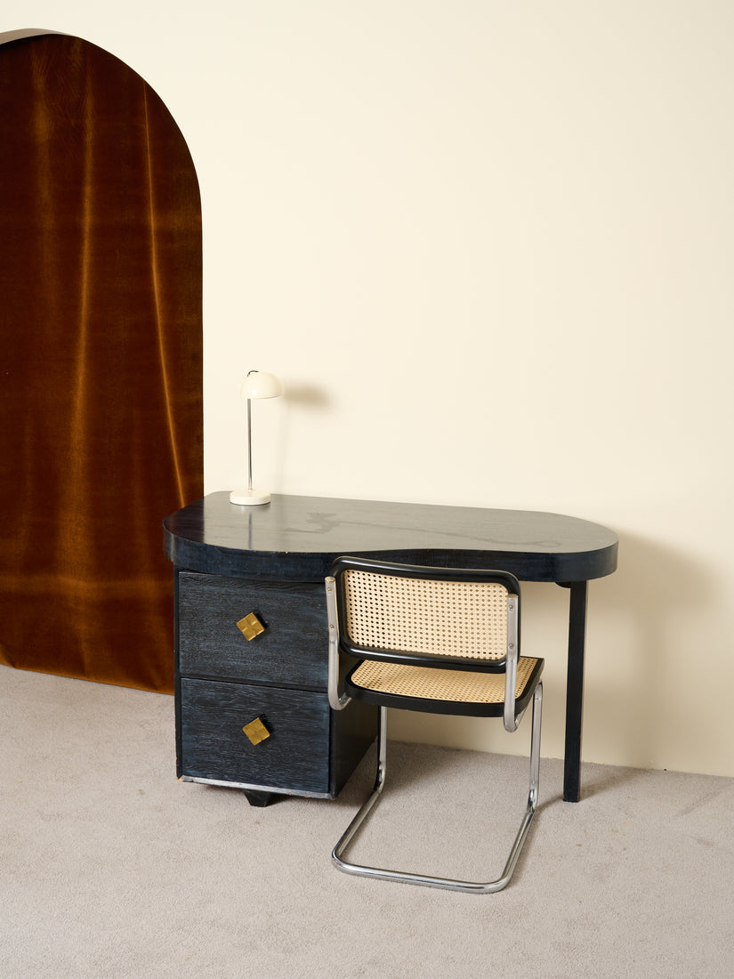 Vintage desk with a white lamp and black Cesca chair.