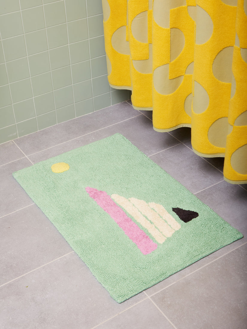 Yacht Club Bath Mat by Cold Picnic on a tiled floor in front of a Curtina shower curtain.