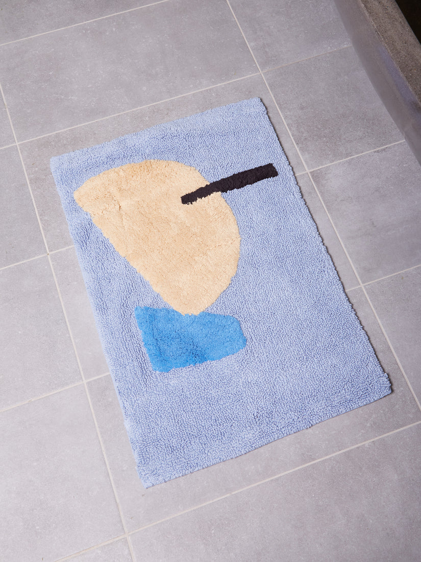 Mostly blue bathmat with abstract forms of cream, brighter blue, and black.