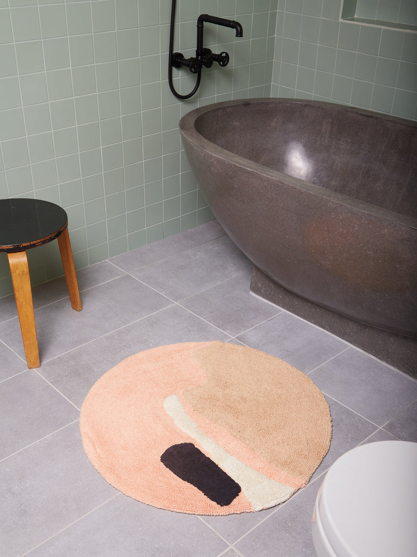 The round Crop Circles Bath Mat by Cold Picnic in a tiled bathroom.