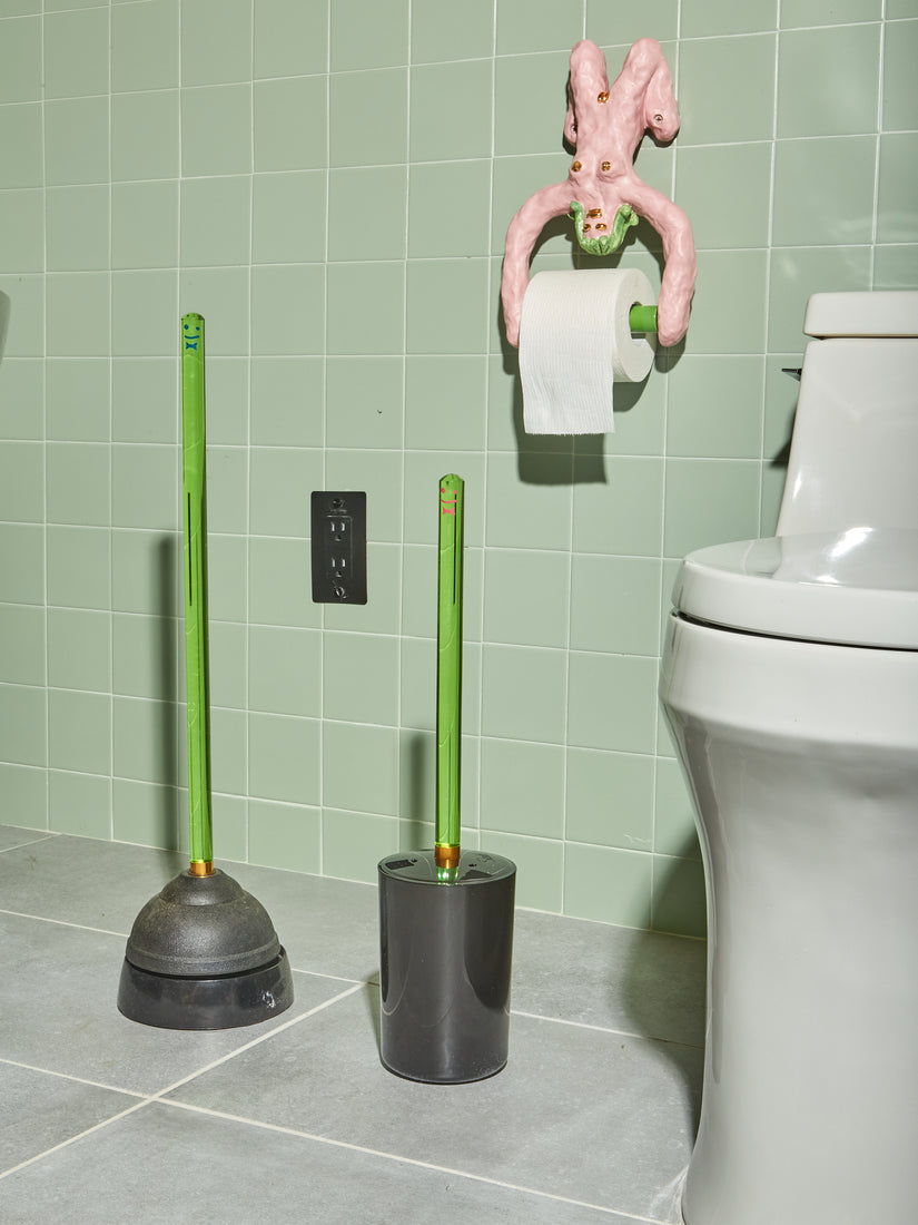 A sage tiled bathroom featuring a green toilet brush and green plunger by Staff.