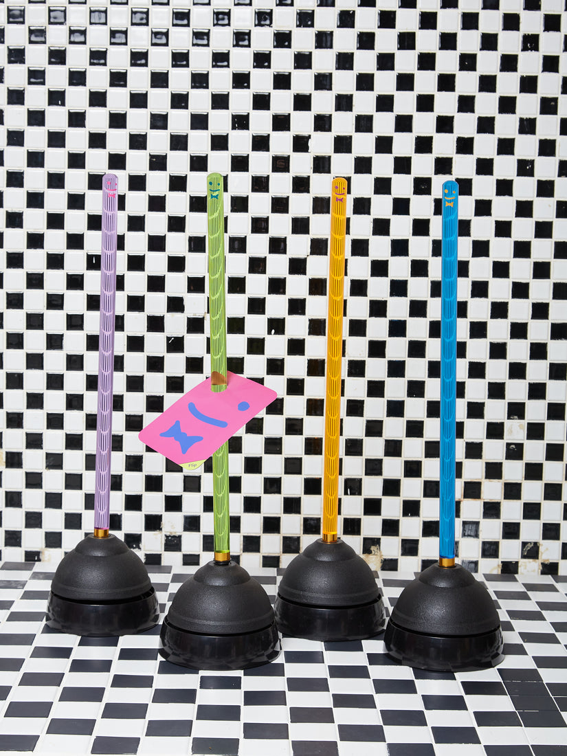 Purple, green, orange, and blue plungers by Staff sitting in a line against a checkered tile.