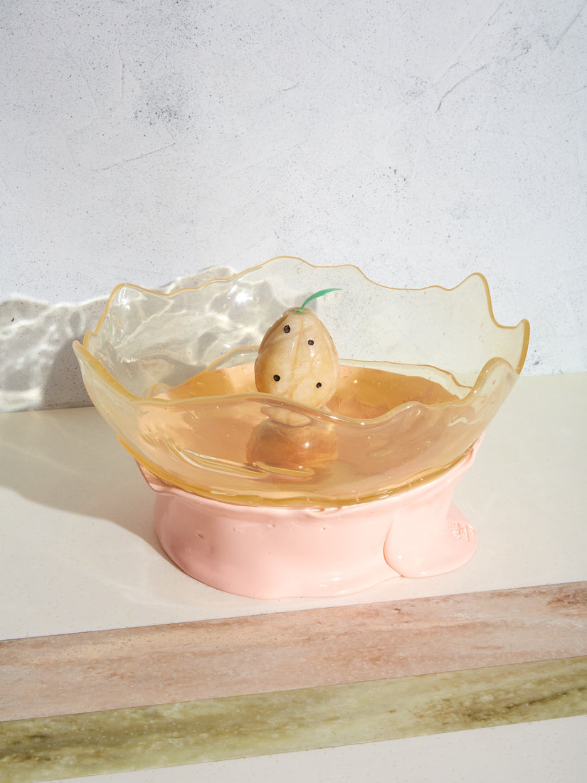 A glass fruit object sitting inside of a clear and pink Big Collina Basket.