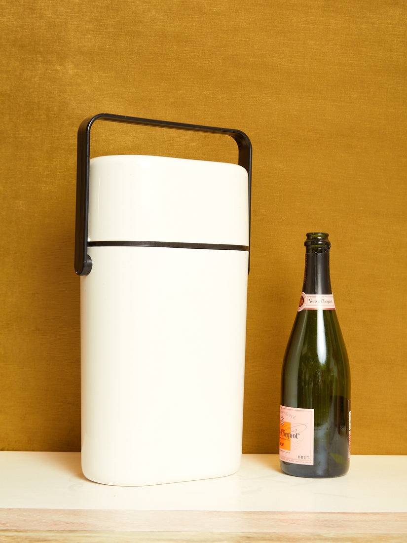 Vintage Travel Wine Cooler in White sitting next to an open bottle of champagne.