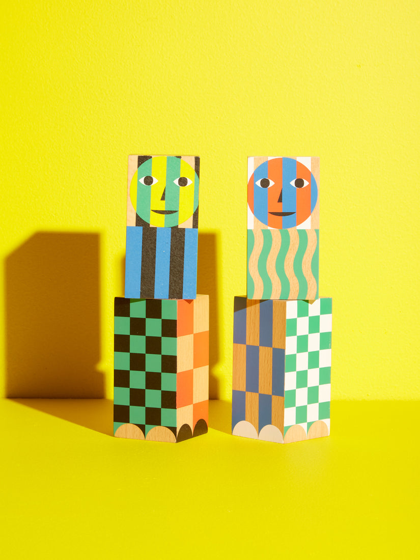 A pair of patterned pepper and salt grinders featuring colorful stripes, squiggles, checkers, and faces by Dusen Dusen for Areaware.