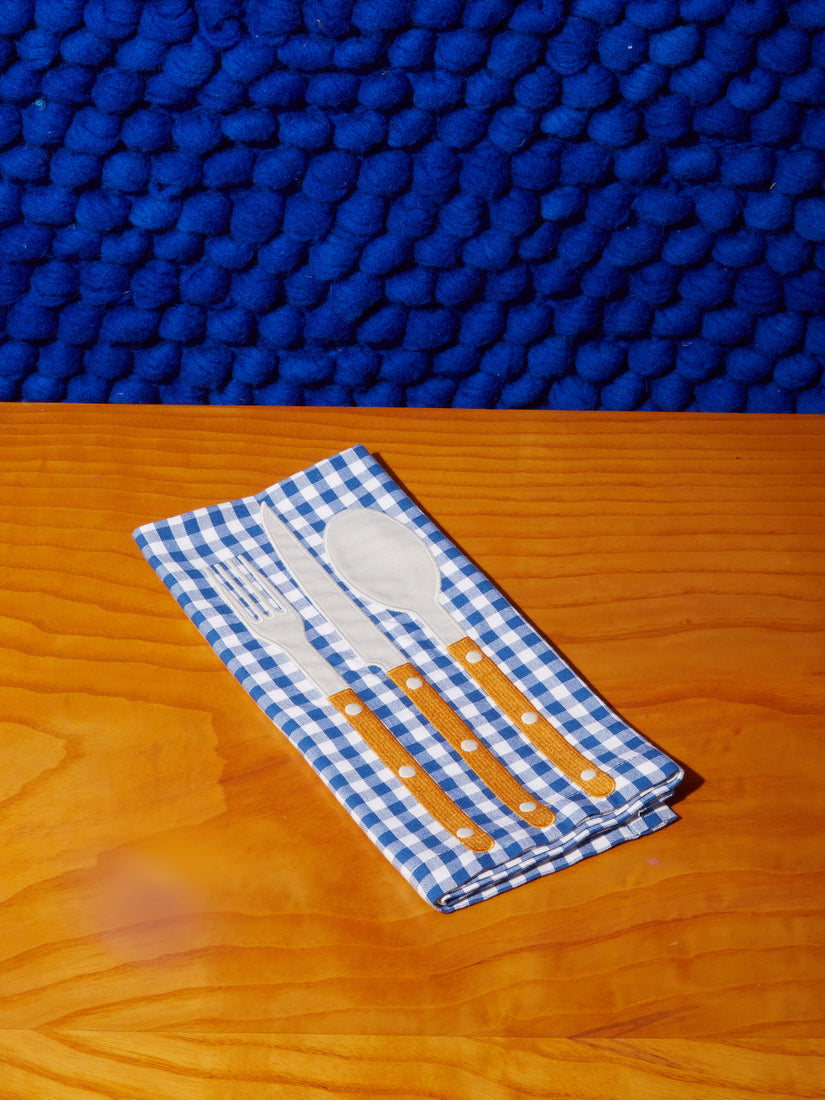 Blue and white gingham napkin wtih embroidered fork, knife, and spoon.