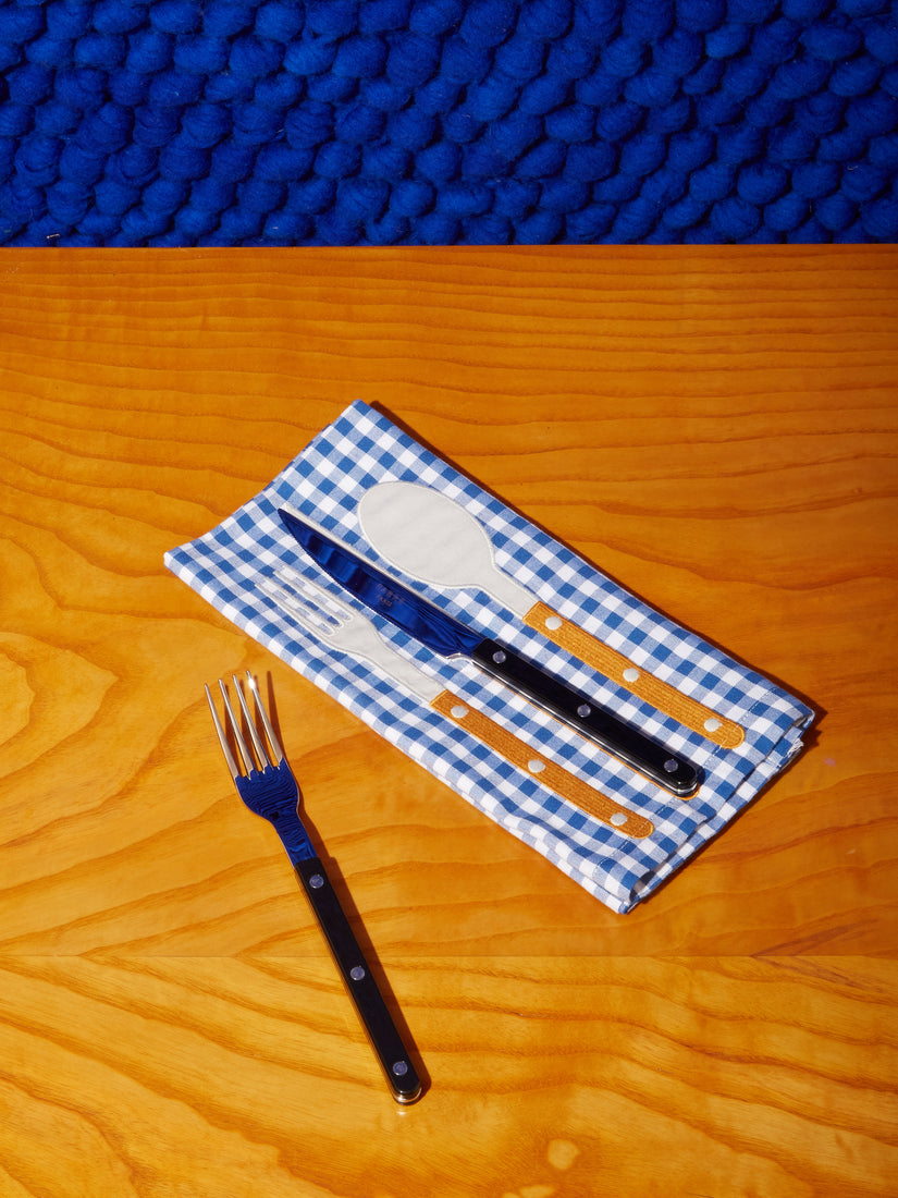 A black fork and knife paired with a La Serviette Napkin.