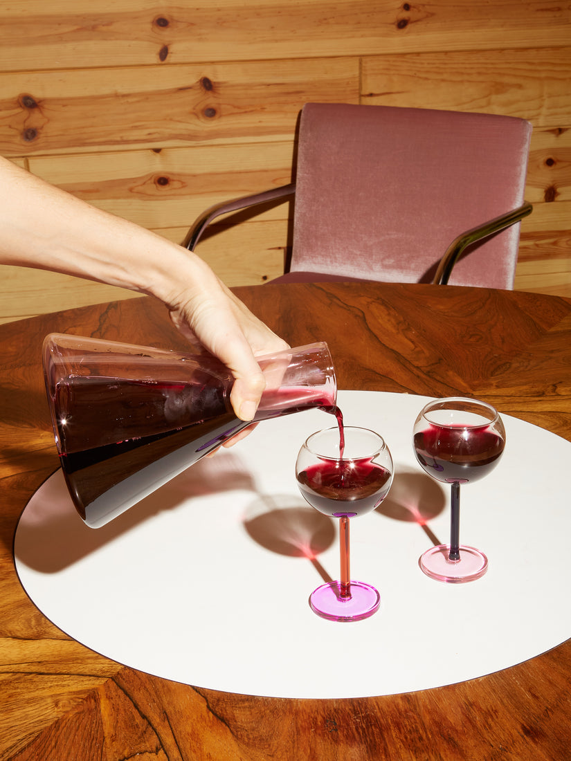 A hand pours red wine into Bilboquet Wine Glasses from a Bilboquet Carafe.