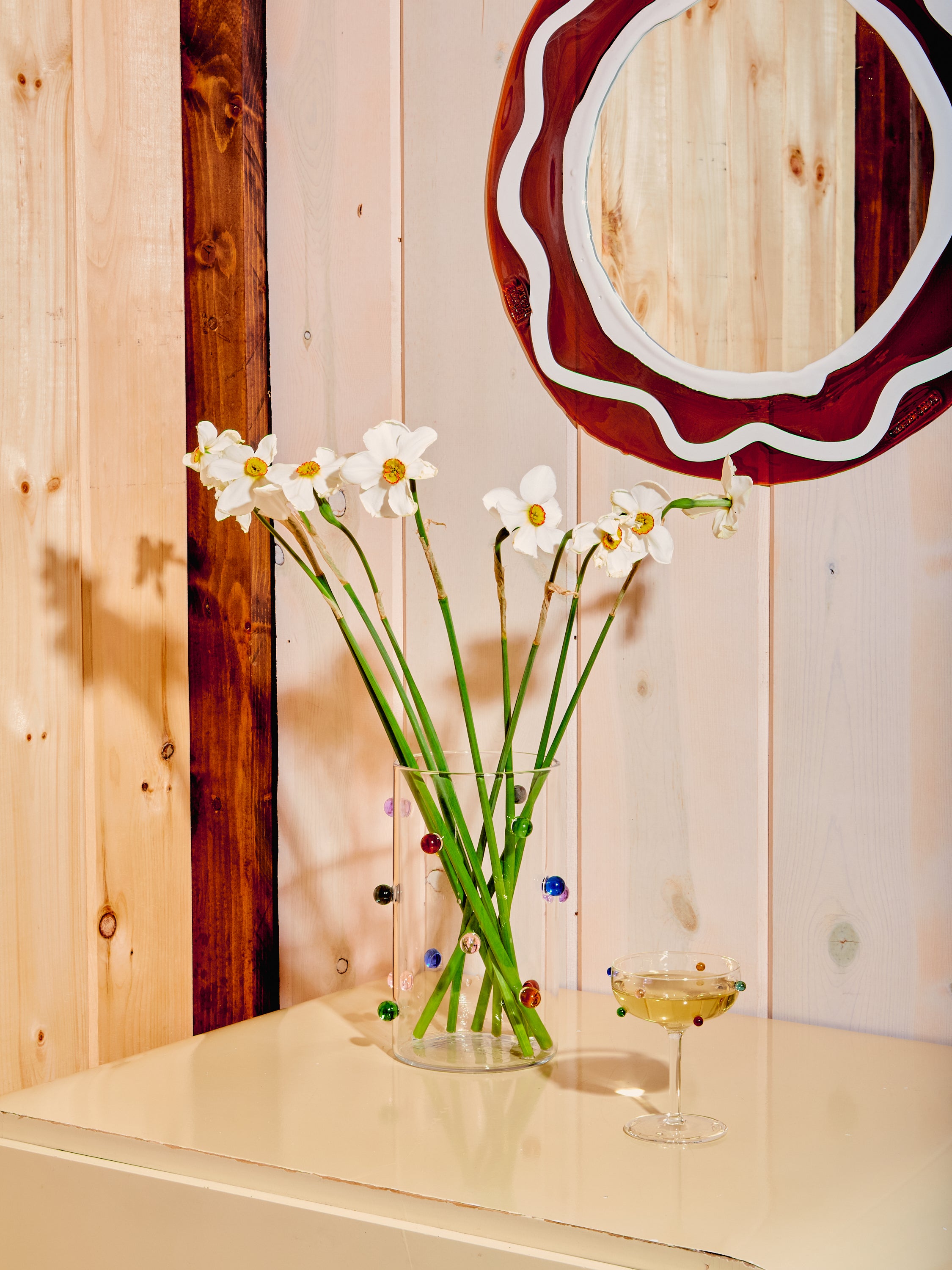 Dot Vase full of white lilies styled with a dot coupe, round mirror, and cream dresser.