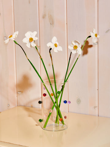 Clear vase with multicolored glass orbs along its exterior.